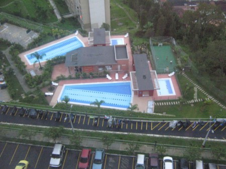 Vista aérea al salón social, cancha de futbol con grama sintética, piscinas, cancha baloncesto, gimnasio, etc